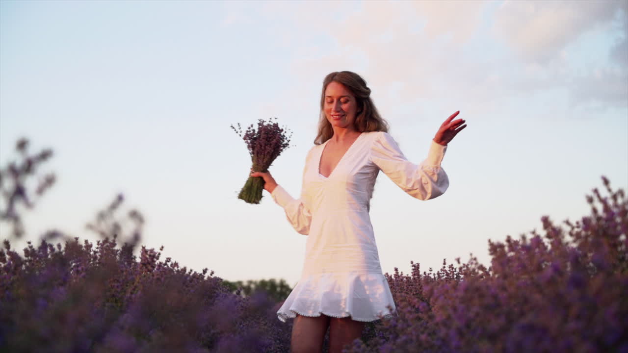 Woman in a white dress spinning through a lavender field
