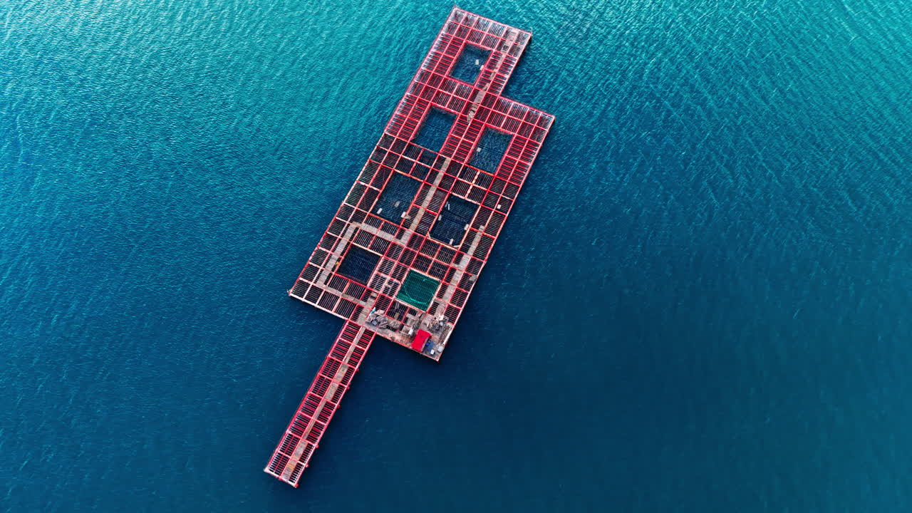 Long rectangular industrial shellfish farming platform in dark blue water. Symmetrical aerial view of floating aquaculture mussel farm