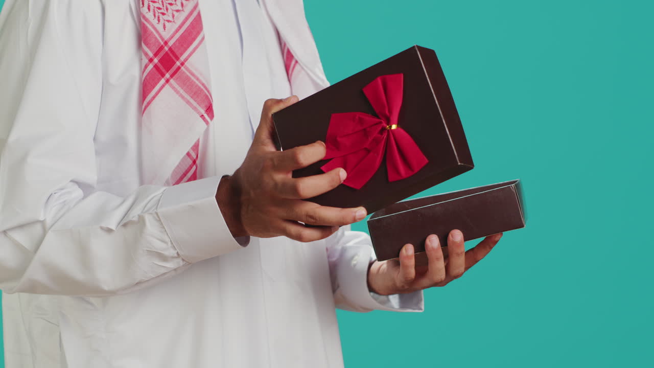 Pria Muslim membuka kotak hadiah dengan pita