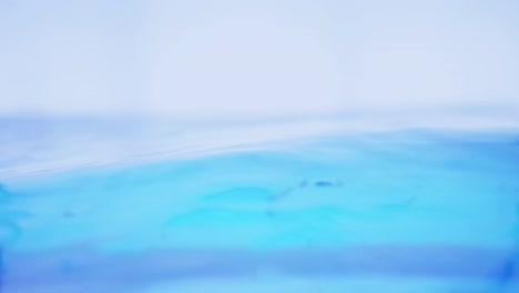 la superficie del agua limpia en cámara lenta llena la pantalla con agua salpicando la gota de agua y la superficie líquida ondeando con una burbuja de aire