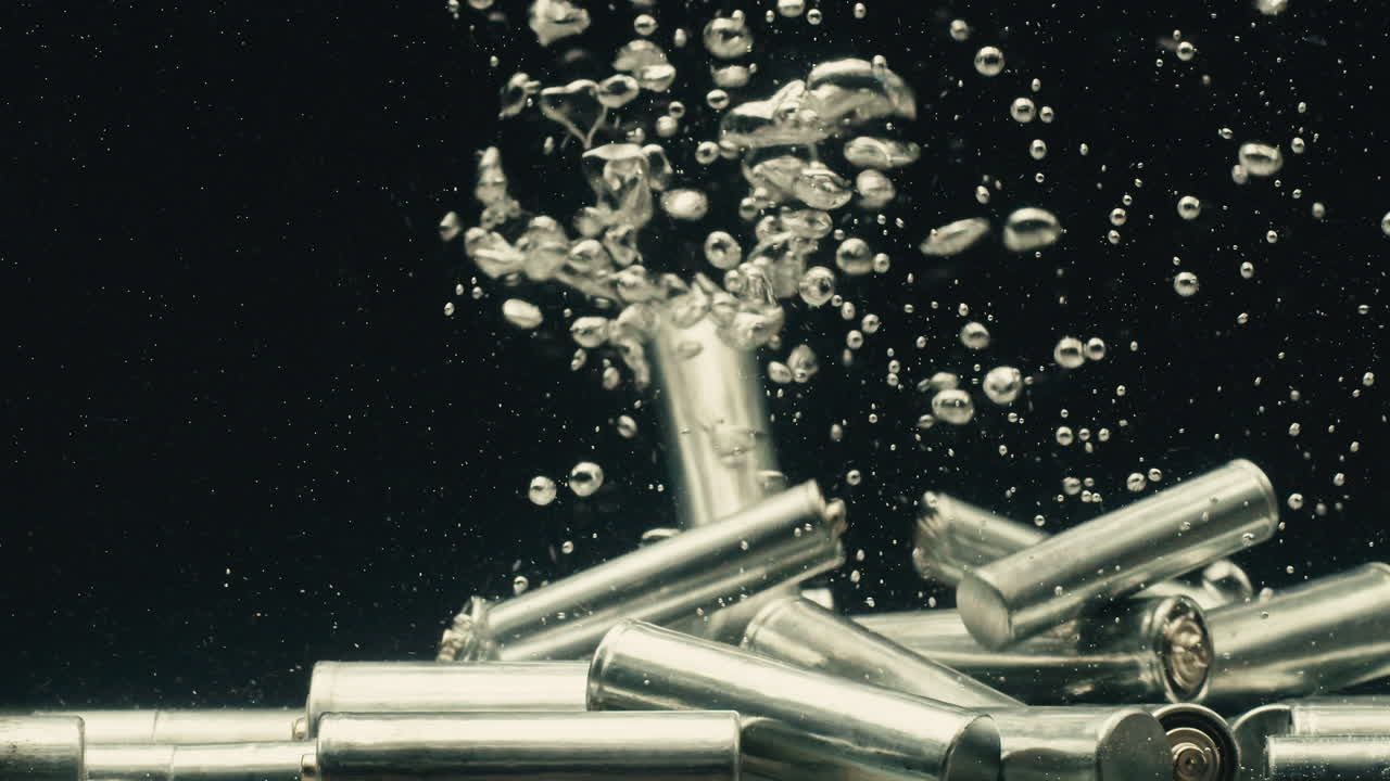 Silver batteries AA and AAA falling into water close-up. Double-A battery is a standard size single cell cylindrical dry battery. Batteries are common in portable electronic devices. Environmental impacts of lithium-ion batteries concept. An AA battery is composed of a single electrochemical cell th