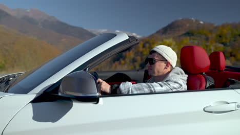 hombre conduciendo un coche descapotable a través de las montañas