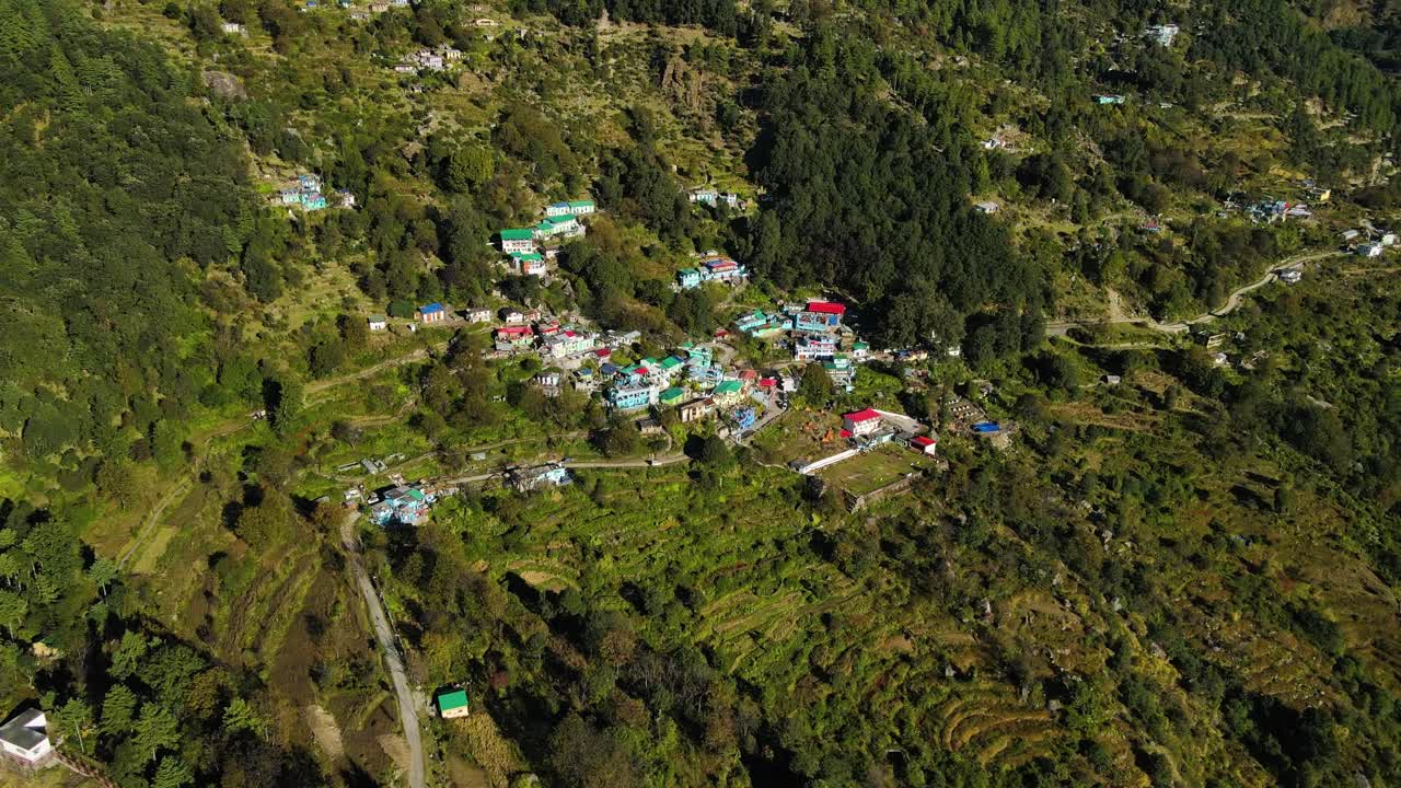 una toma aérea de un dron que muestra un tranquilo pueblo de montaña con carreteras sinuosas a través de laderas verdes y exuberantes.