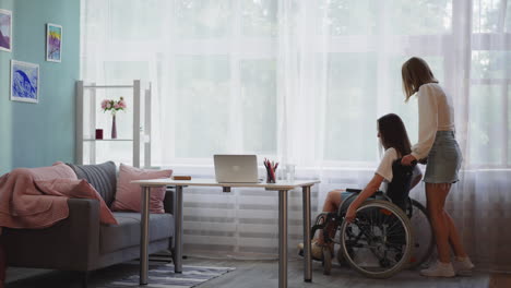 una mujer joven ayuda a su hermana con discapacidad en silla de ruedas a llegar a la mesa