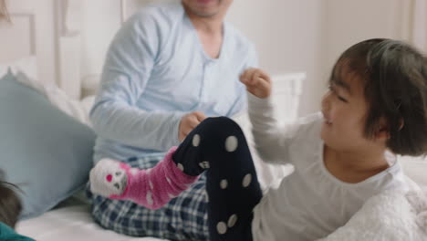 familia asiática feliz con niños saltando en la cama jugando con la madre y el padre divirtiéndose en la mañana del fin de semana emocionados niños pequeños disfrutando del juego con los padres en casa imágenes 4k