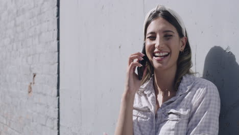 mujer joven riendo mientras habla por teléfono