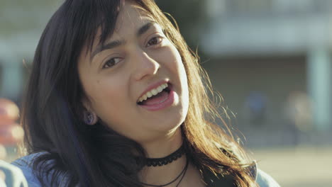 un primer plano de una morena sonriente hablando con la cámara.