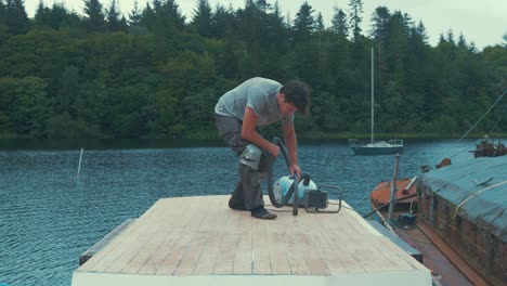 young man hoovering dust remnants from sanding wooden boat roof