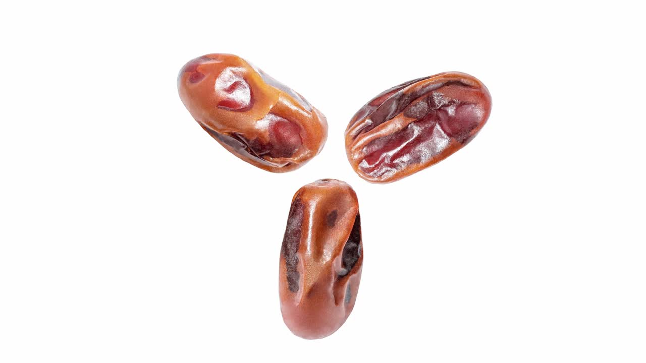 Dates dried, three pieces close-up, rotating isolated on white, macro, top view.