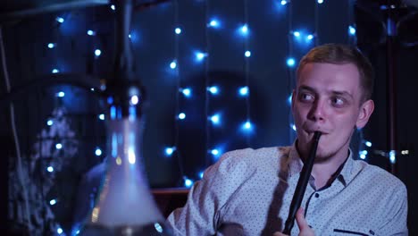 hombre fumando narguile en un club nocturno