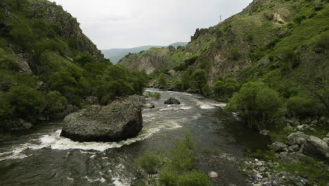 rocky river flowing in the great caucasus mountains at the base of tmogvi castle mount, samtskhe-javakheti region, georgia