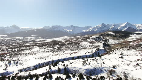 Aerial-Cinematic-drone-mid-winter-of-San-Juan-Mountain-Range-Ridgway-Telluride-Our-Mt-Sneffels-14er-stunning-ranching-farm-land-of-Colorado-early-morning-mid-winter-blue-sky-pan-backward-movement