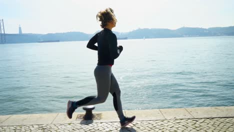 mujer joven atlética en ropa deportiva corriendo cerca del río