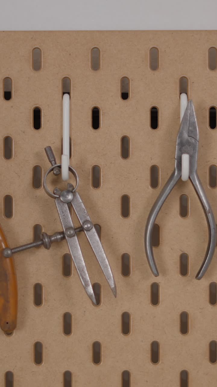 A hand reaching for tools organized on a pegboard in a workshop