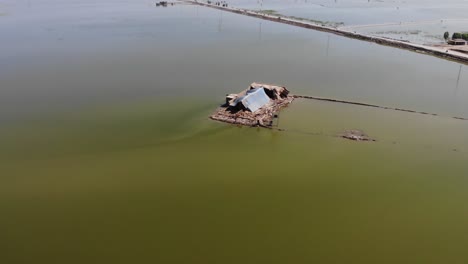 Drohne-Macht-Eine-Luftaufnahme-Des-Zerbrochenen-Hauses-Und-Des-Umliegenden-Feldes,-Das-Wegen-Einer-überschwemmung-In-Pakistan-In-Wasser-Getaucht-Ist