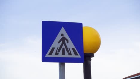 Unregulated pedestrian crossing sign against blue sunset sky. Yellow round traffic light flashing