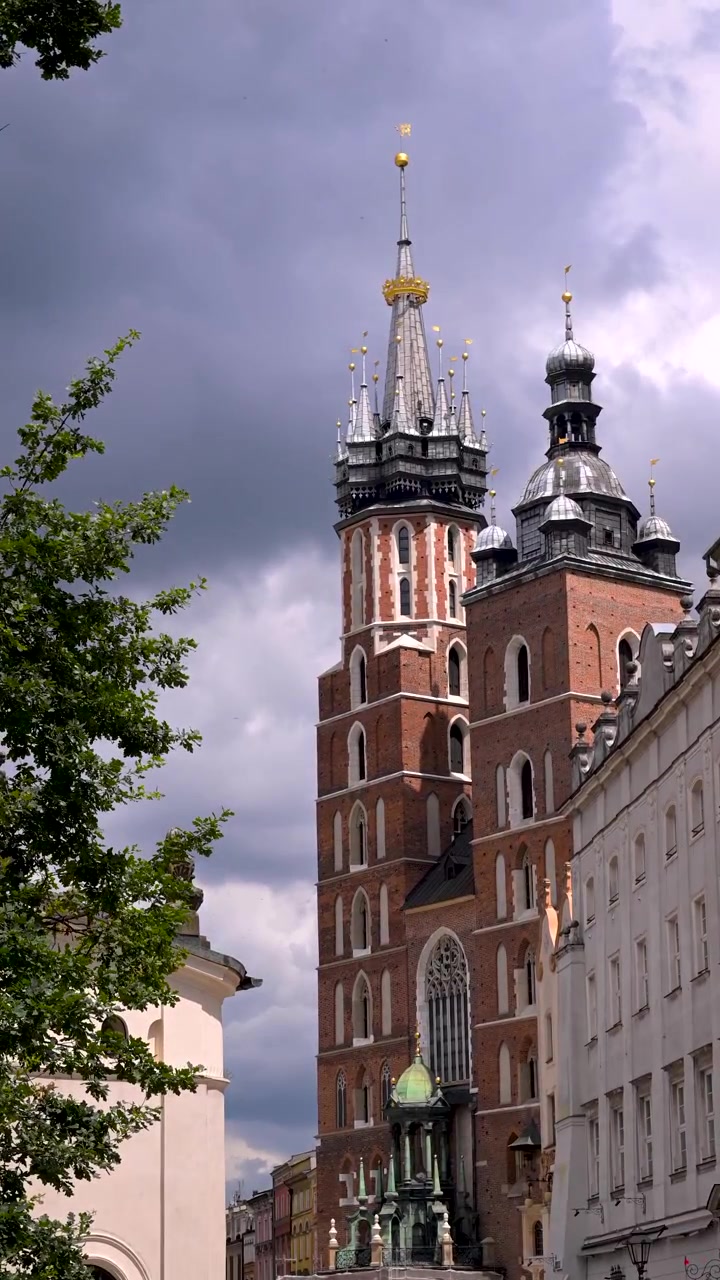 La Basilica di Santa Maria si erge sopra la Città Vecchia di Cracovia mentre scure nuvole temporalesche si addensano dietro le sue torri gemelle in mattoni.
