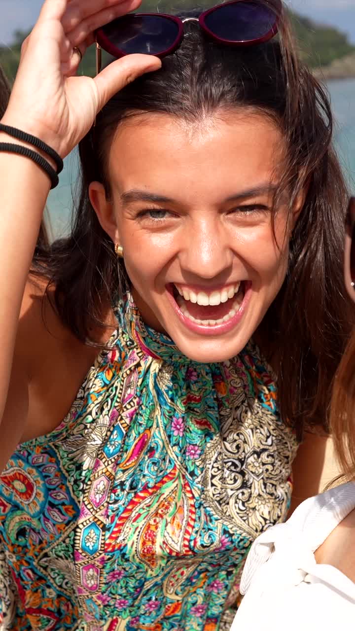 Due giovani donne felici che sorridono e ridono su una spiaggia assolata.