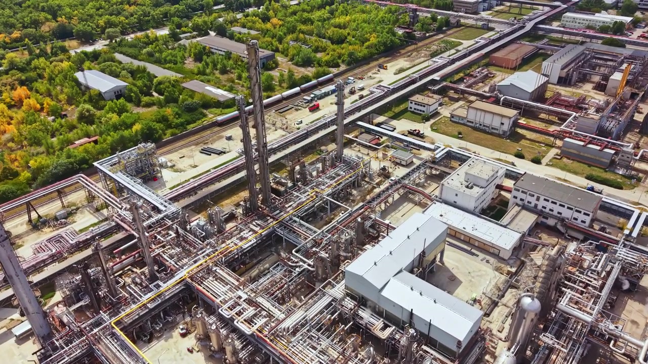 Industrial site with pipelines and buildings seen from above on a clear day with greenery around