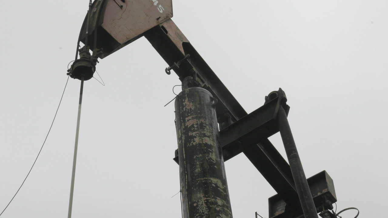 시간 경과에 따라 구름이 푸른 하늘을 가로질러 지나가면서 오일 펌프 잭이 오르락내리락합니다.