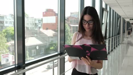 una morena de negocios con gafas toma notas en el pasillo de la oficina