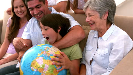 extended family looking at globe together on couch