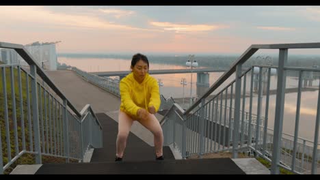woman doing squats on stairs outdoors