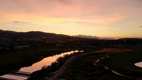 aerial hyperlapse with a colorful sunset reflecting off the surface of a river and lake in a suburban area