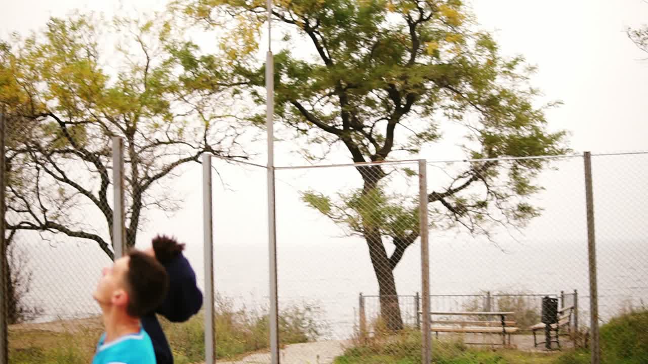 dos jóvenes amigos multiétnicos juegan al baloncesto en la calle. un tipo consigue una pelota en la canasta. disparo en cámara lenta