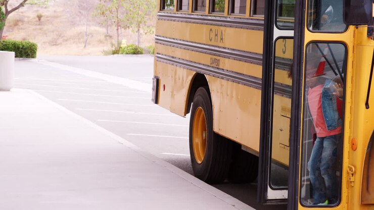 Elementary schoolchildren getting off school bus in morning