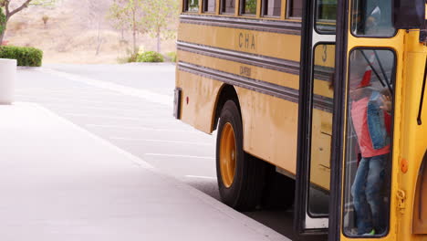 elementary schoolchildren getting off school bus in morning