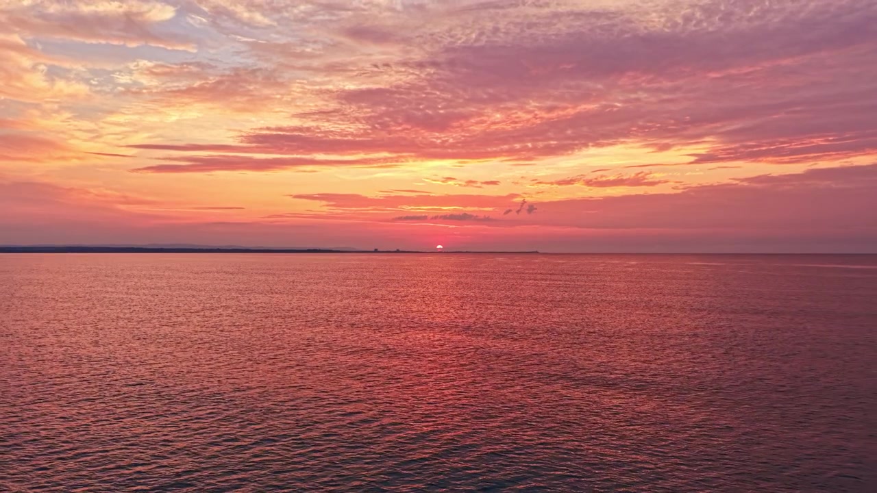Solnedgang over havet med farverige skyer ved kysten om aftenen