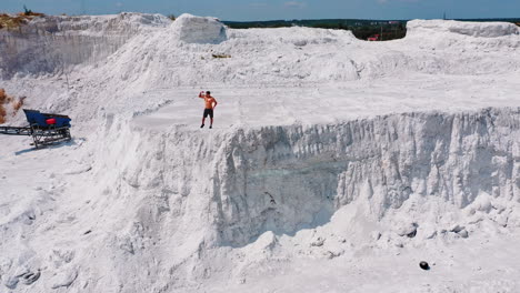muscular sportsman on a white hill. view from above on a strong guy who is showing his strength on the natural background. bodybuilder on a rocky canyon. aerial view.