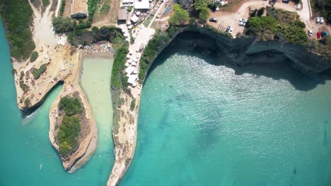 Aerial-top-down-scenic-summer-paradise-with-tourist-sunbathing-in-sandy-beach-and-sail-boat-on-the-Mediterranean-Sea