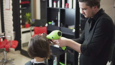 Professional-hairdresser-is-drying-hair-of-young-attractive-woman-in-beauty-salon.-Shot-in-4k