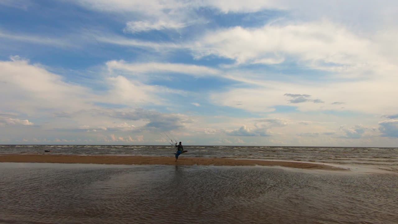 kitesurfista caminando hacia las olas con su tabla y cometa