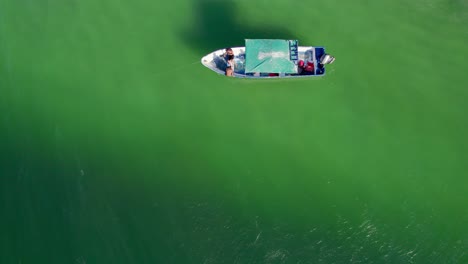 top down birdseye drone view of fishing boat in green ocean water off costa rica, 4k aerial