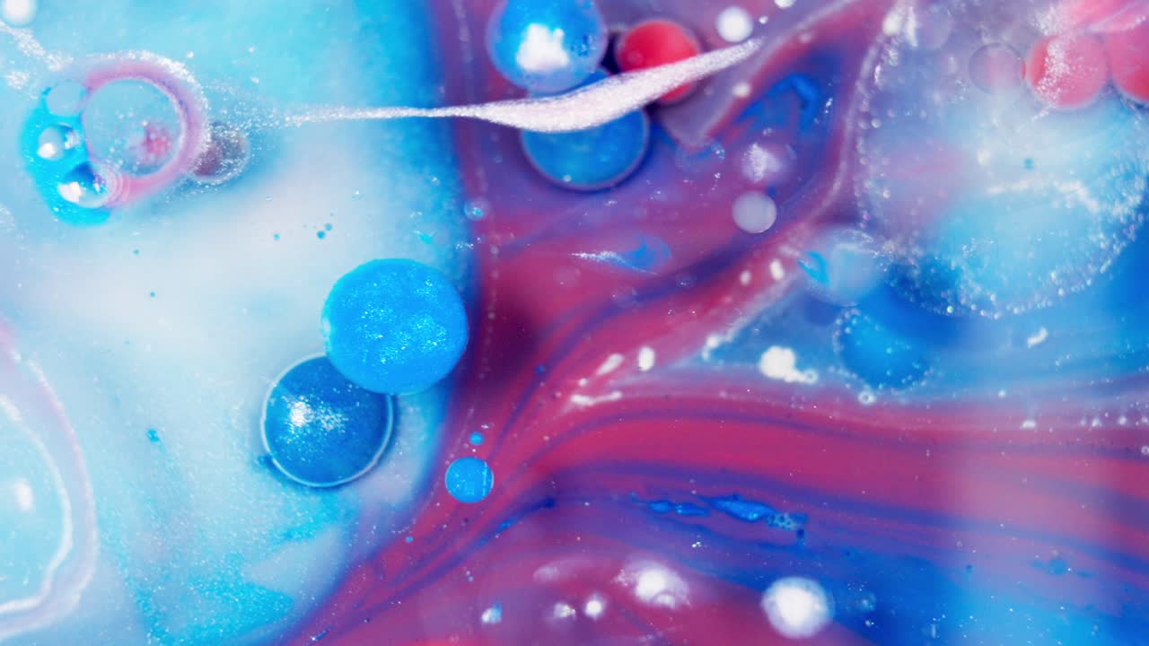 Fluido di colore blu che si increspa attraverso inchiostro liquido rosso e viola, astratto.