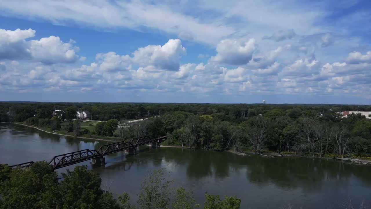 Drone footage over a field, over a river, and into a small Midwest town