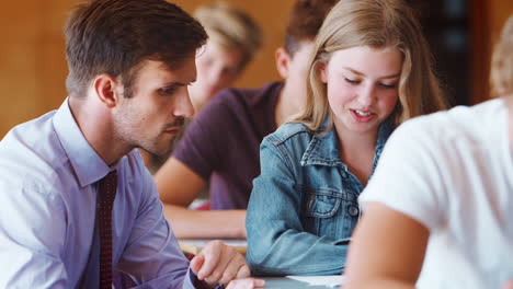 female college student sitting examination talking with teacher