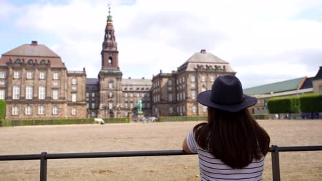 woman with a hat looking at the horses outside christiansborg palace, denmark