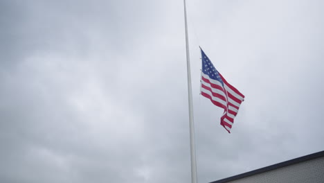 american flag is solemnly displayed at half-mast, fluttering gently in the wind