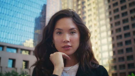 cute woman smiling on camera outdoors. asian model posing in front of buildings.