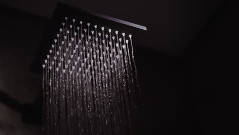 el agua fluye de una boquilla cuadrada negra en la ducha.