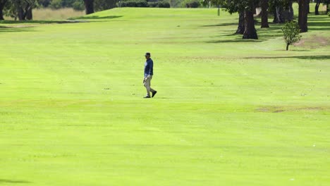 a golfer strolls on a vibrant green fairway