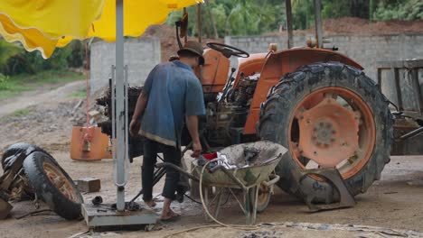 man repairing tractor in rural setting