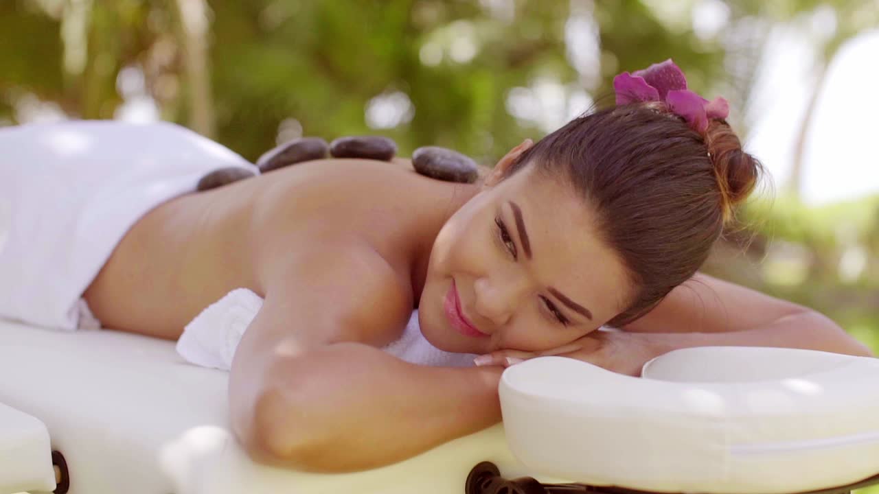 una mujer joven y bonita teniendo un masaje de piedras calientes