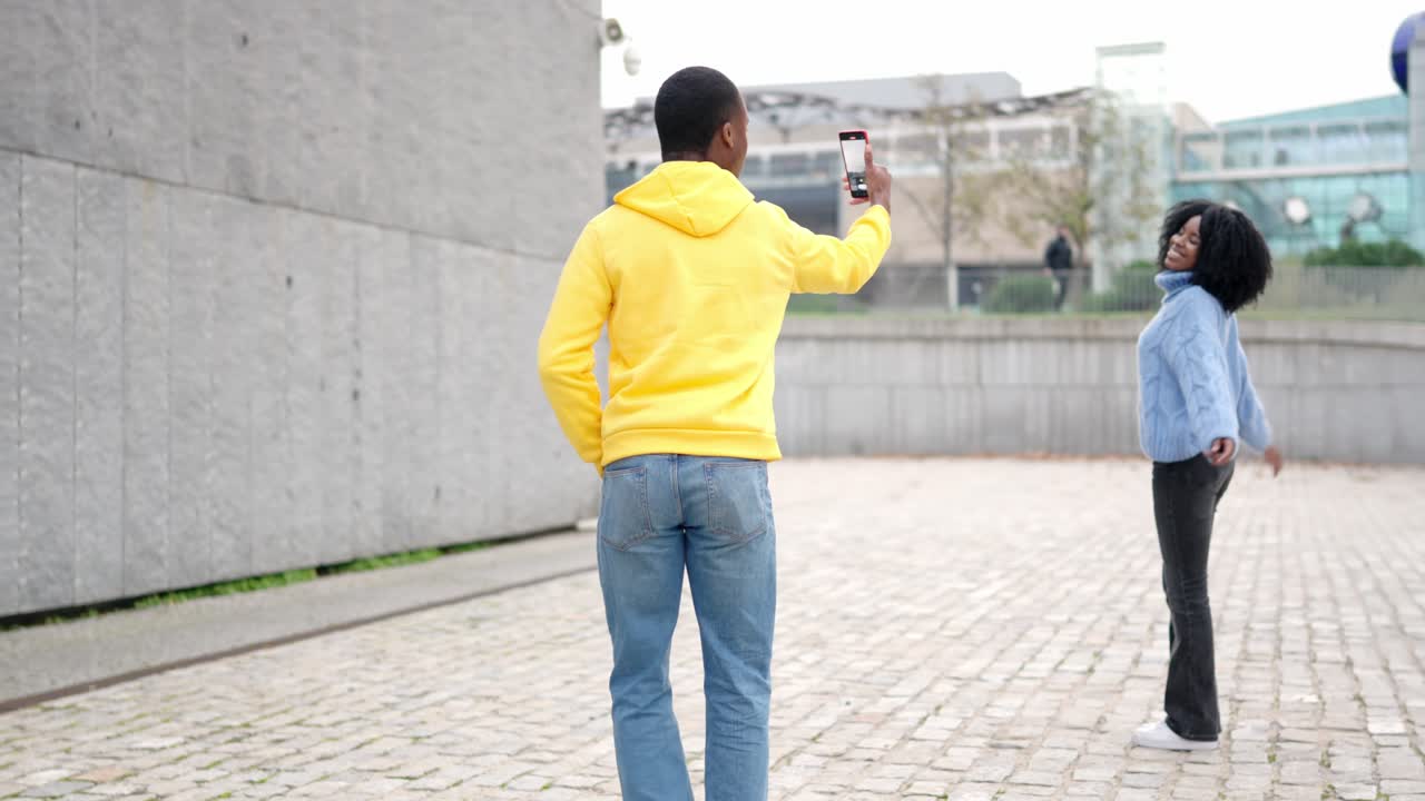 African woman posing while her couple taking photos of her