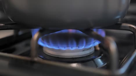 gas stove top with blue flames under a pot