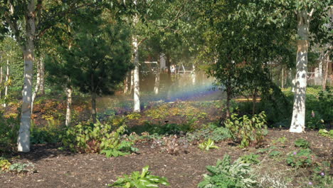 sistema de rociadores en zona boscosa, creando un arco iris bajo el sol, bloqueado